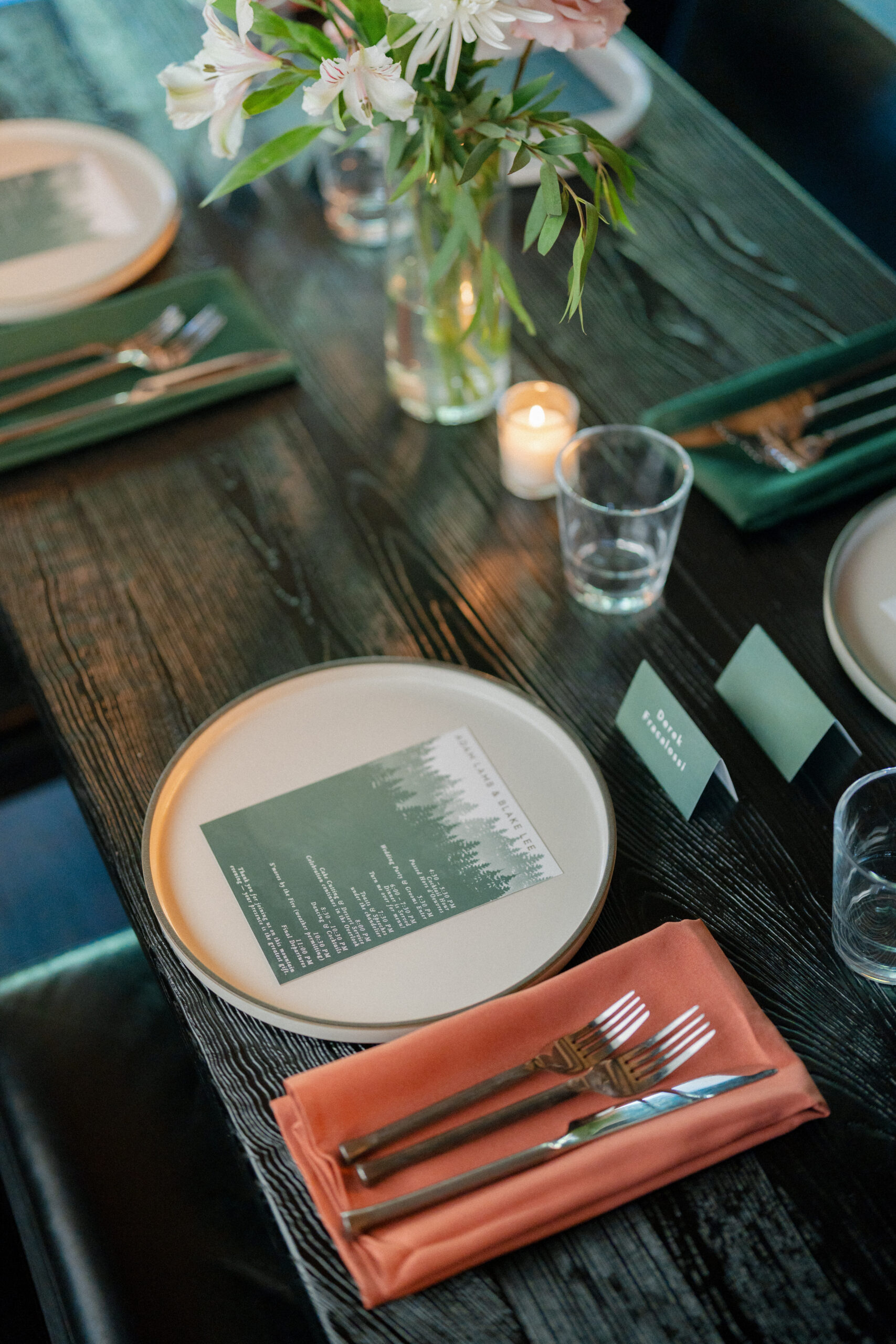 A wedding tablescape with menu card, blush napkin, and greenery